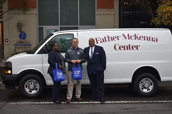 APAF Staff posing for photo with Dennis Dee in front of a Father McKenna Center van