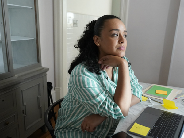 Woman sitting at desk with laptop staring into the distance