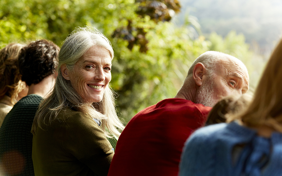 Woman sitting with a group outside similing at camera