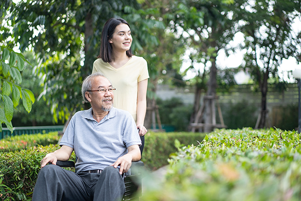 Woman pushing elderly man in a wheelchair